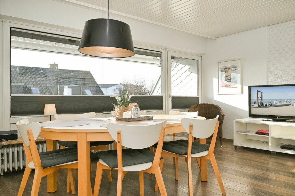 Un salon moderne comprenant une table à manger, des chaises, un téléviseur et de grandes fenêtres.