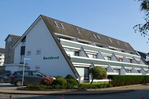 A multi-story building with a flat roof and a sign reading 'Backbord.' - Holiday apartment in Büsum with swimming pool (Büsum)