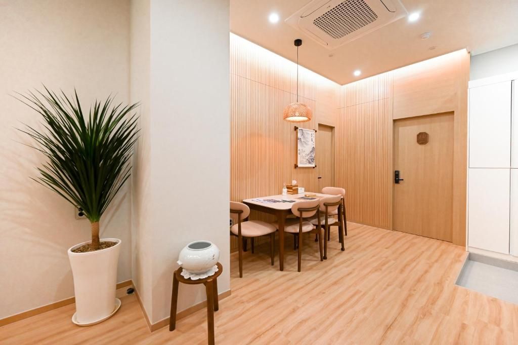 A modern interior with a dining area featuring a round table and chairs, a potted plant, and a wooden door.