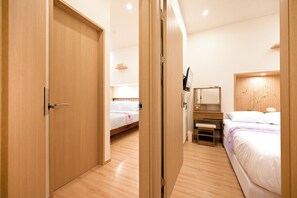 A hotel room with wooden flooring, two beds, a bedside table, a mirror, and a small shelf. - SO ON Stay (Seoul)
