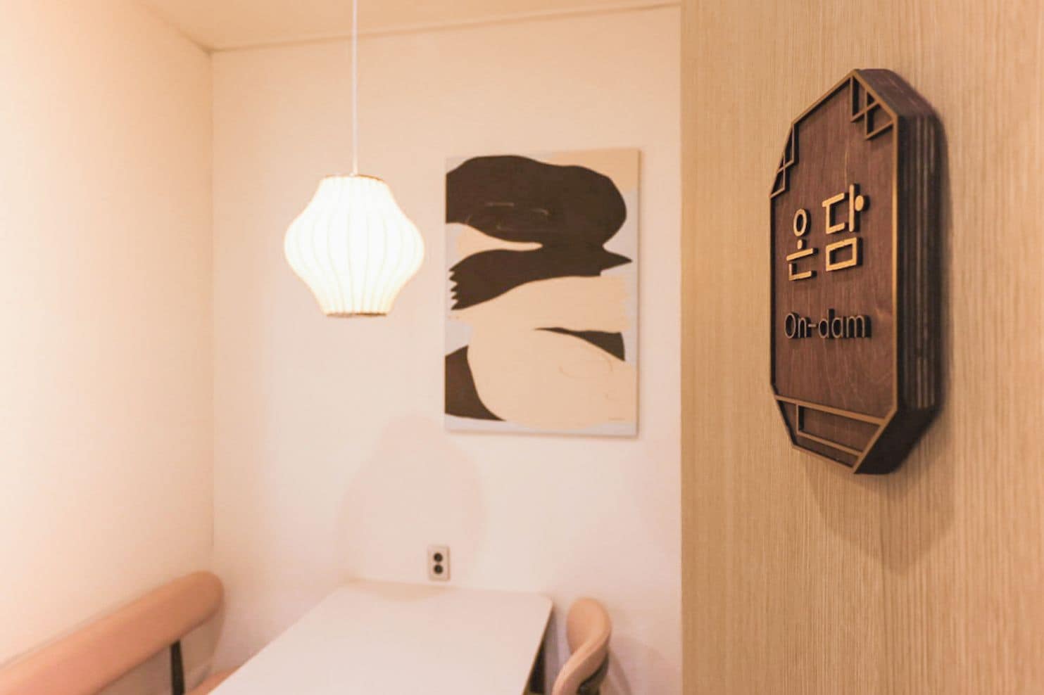Ein Zimmer mit einem an der Wand befestigten Holzschild, einer Hängeleuchte und einem gerahmten Kunstwerk.