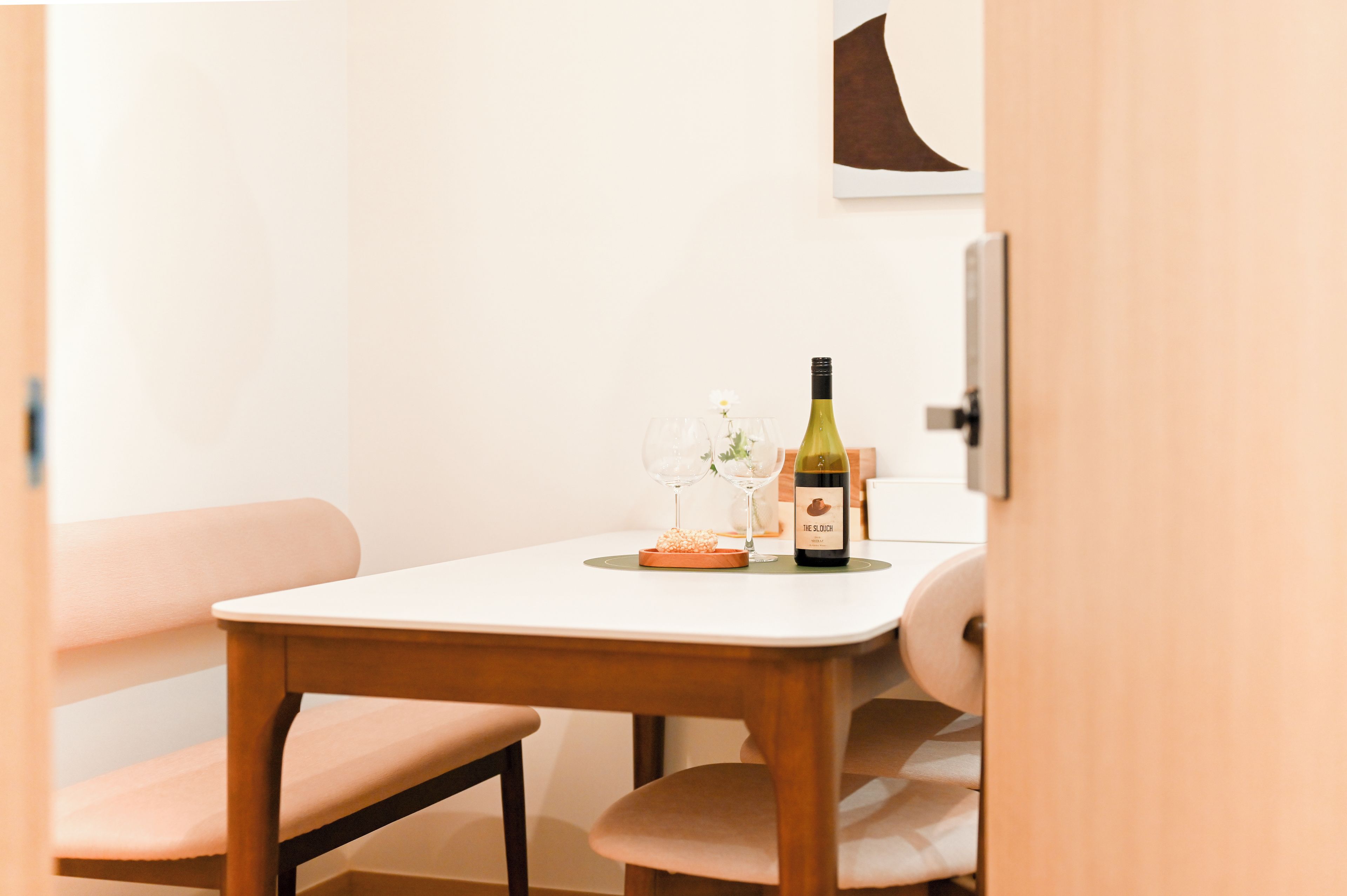 A dining table with a bottle of wine, glasses, and a small bowl of snacks.