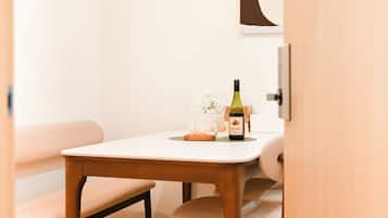 A dining table with a bottle of wine, glasses, and a small bowl of snacks.