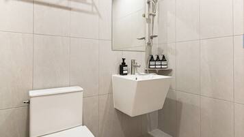 A modern bathroom with a toilet, sink, and shower.