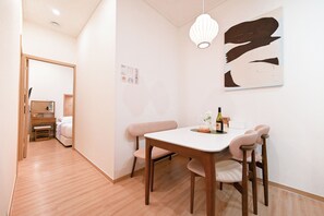 A modern room with a dining table, chairs, a hanging light fixture, and a wall-mounted artwork. - SO ON Stay (Seoul)