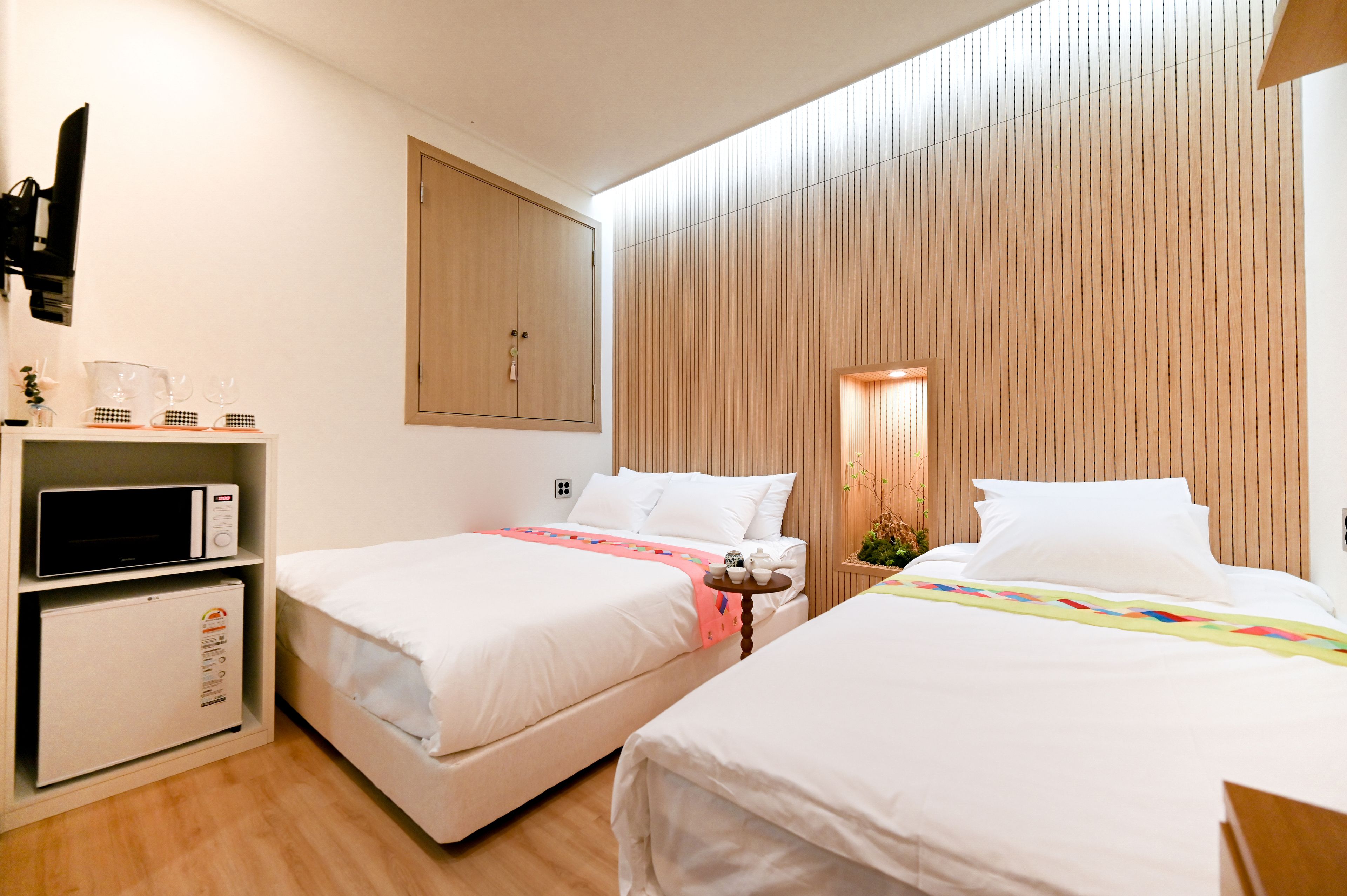 A hotel room with two beds, a microwave, a small refrigerator, and a wooden panel wall.