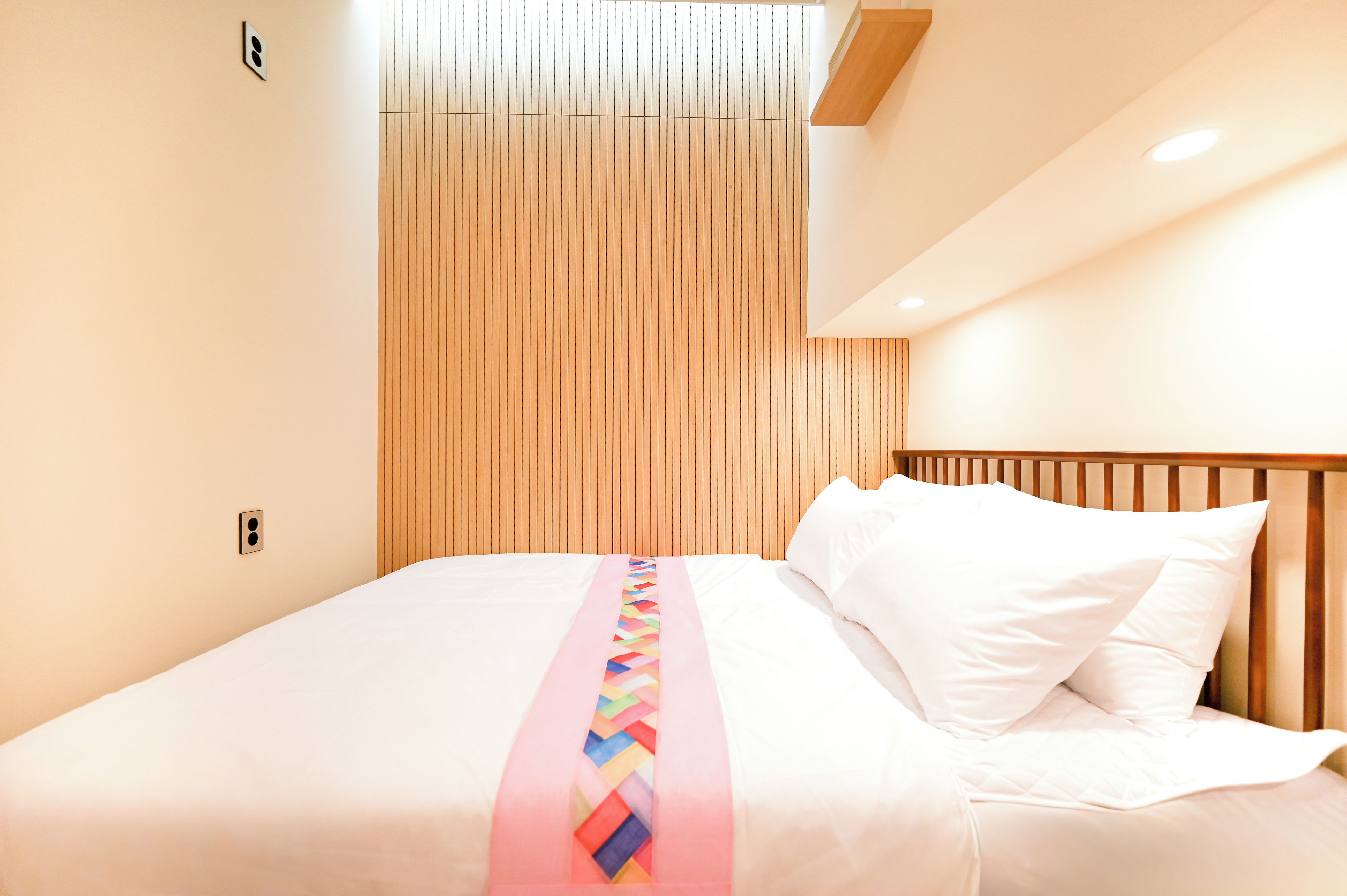 Ein Hotelzimmer mit einem Bett, einem Holz-Kopfteil und einer Wandleuchte.