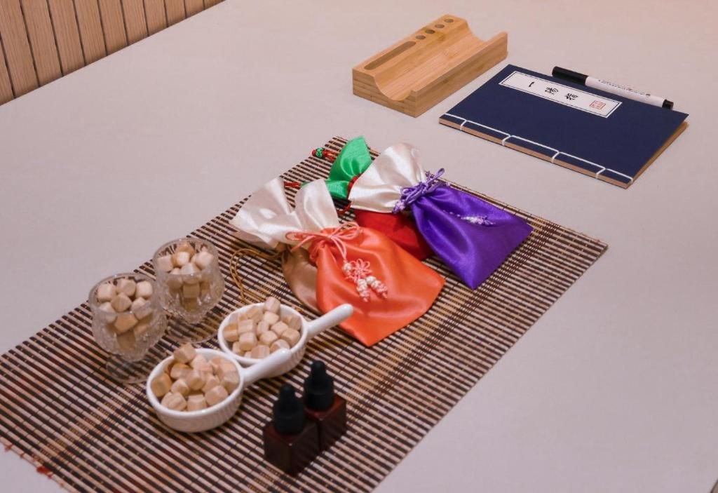 A table with a notebook, a pen, and various items including a wooden block, a woven mat, and small containers with cubes.