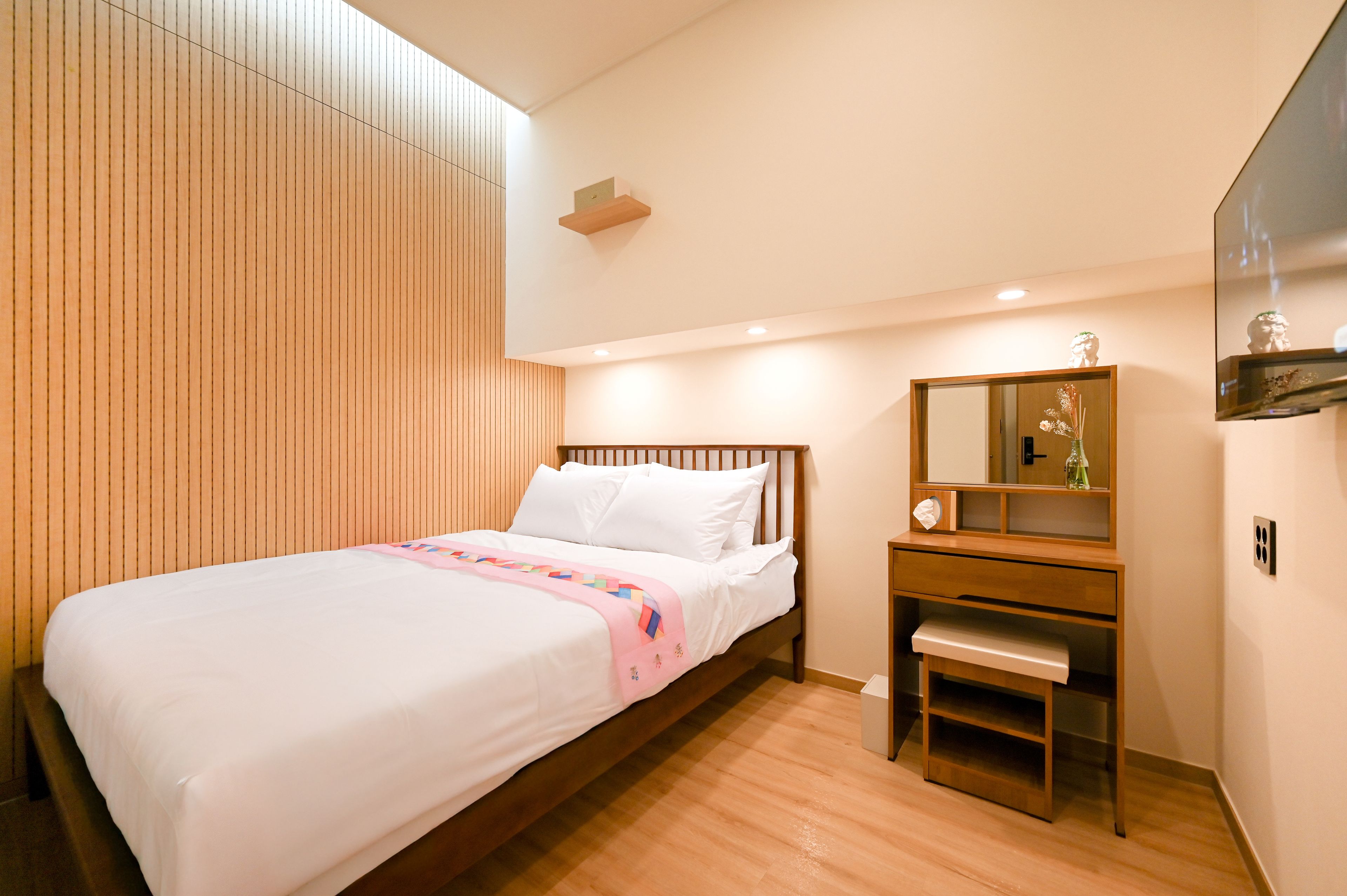 A hotel room with a bed, a desk, a mirror, and a wardrobe.