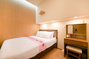 A hotel room with a wooden headboard, a bed with white bedding, a bedside table with a mirror, and a small shelf. - SO ON Stay (Seoul)