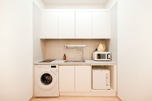 A compact kitchenette with a washing machine, a microwave, and a sink. - SO ON Stay (Seoul)