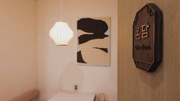 Una habitación con un letrero de madera montado en la pared, una lámpara colgante y una obra de arte abstracta.