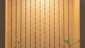 Pared vertical de madera con un hueco que muestra una formación rocosa, musgo y plantas pequeñas.