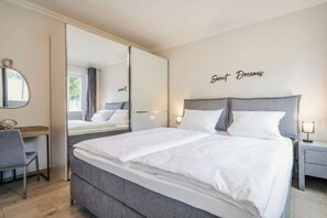Ein modernes Hotelzimmer mit einem großen Bett, einem Schreibtisch und einem Spiegel.