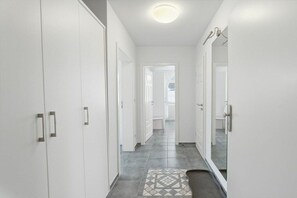 A hallway with white doors, a patterned rug, and a ceiling light. - Evening - Apartment 4 (Zingst (Ostseeheilbad))