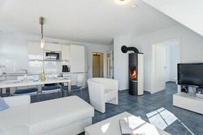 A modern living space with a kitchen, dining area, and a fireplace. - Evening - Apartment 4 (Zingst (Ostseeheilbad))