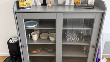 Ein Küchenschrank mit Stauraum für Geschirr, Gläser und eine Kaffeemaschine.