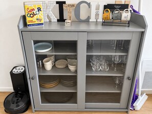 Un armario de cocina con estantes para guardar platos, vasos y una máquina de café.
