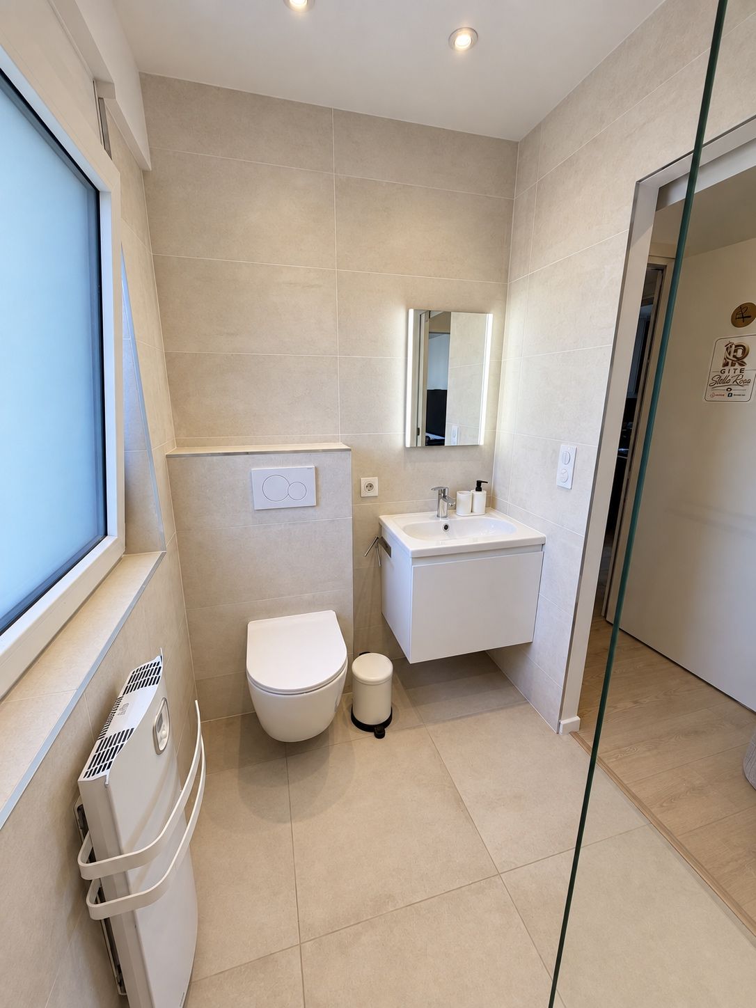 A modern bathroom with a toilet, sink, and mirror.