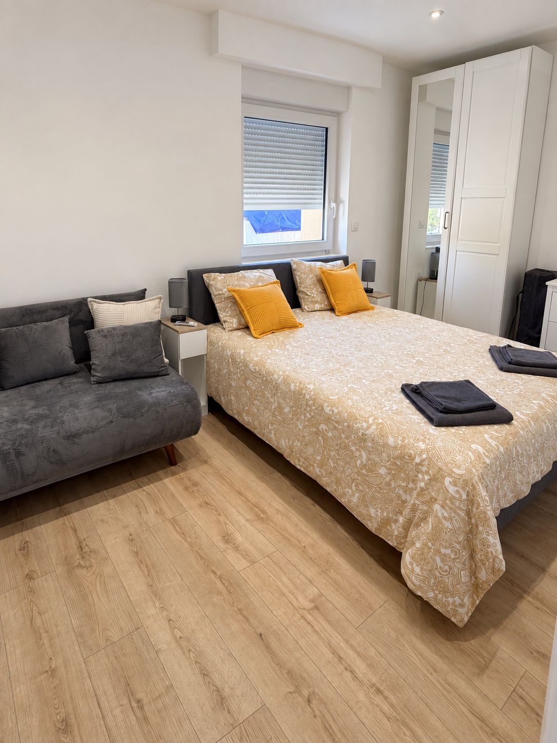 Une chambre à coucher comprenant un lit, un canapé, une table de chevet et une armoire.