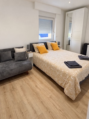 A bedroom with a bed, a sofa, a nightstand, and a wardrobe. - Stella Rosa Vacation Rental — Private, air-conditioned apartment with self-check-in (Soleuvre)