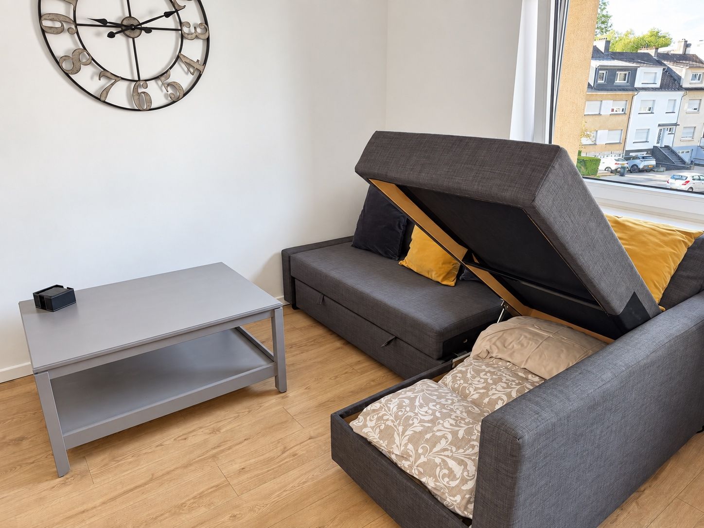 A modern living room with a sofa, a coffee table, and a wall clock.