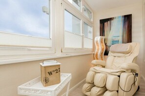 Un fauteuil de massage dans une pièce avec une fenêtre et un tableau au mur.