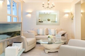 A living room with a sofa, a glass coffee table, a flat-screen TV, and a large mirror on the wall. - Holiday apartment with 2 bedrooms (Ostseebad Binz)