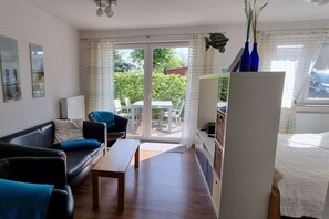 A modern living room with a sofa, coffee table, and a dining area with chairs. - House of Four Elements (Zinnowitz)