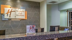 A reception area with a sign for Holiday Inn Club Vacations, a reception desk, and a wall with a geometric tile pattern. - Family Escape Awaits at Holiday Inn Club Vacations Smoky Mountain Resort- 2 Bd. (Gatlinburg)