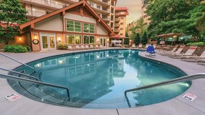 A hotel with a swimming pool, lounge chairs, and a building with multiple balconies.