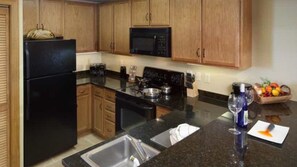 A kitchen with wooden cabinets, a black refrigerator, a microwave, a stove, and a sink. - Family Escape Awaits at Holiday Inn Club Vacations Smoky Mountain Resort- 2 Bd. (Gatlinburg)