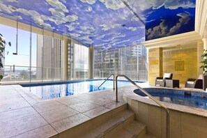 Ein moderner, überdachter Pool mit freiem Blick auf die Stadtkulisse durch große Fenster.