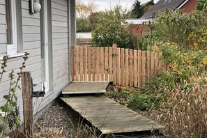 En träaltan som leder fram till ett hus med vit fasad och ett trästaket.