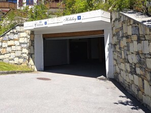 Ein überdachter Parkbereich mit einer Steinmauer und einem Schild, das einen Stellplatz für Feiertage kennzeichnet.
