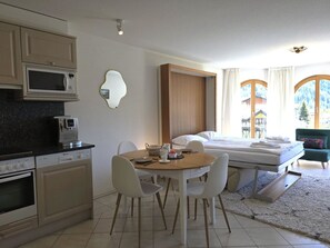 A compact hotel room with a kitchenette, a dining area, a bed, and large windows. - Château 15 # 2-bed apartment, Dusche, WC 2-bed apartment, Dusche, WC by Interhome (Leukerbad)