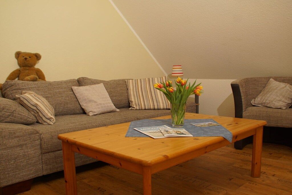 Una sala de estar acogedora con un sofá, una mesa de centro de madera y un osito de peluche.