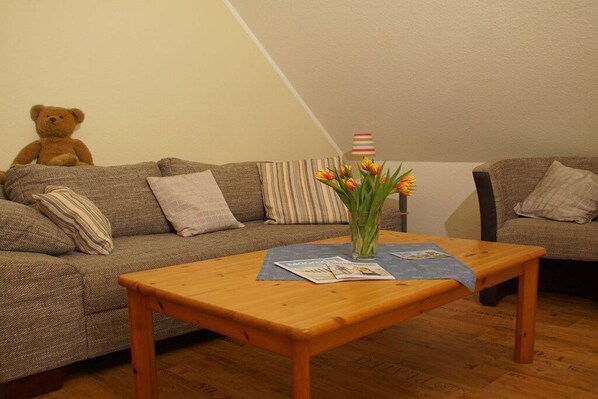 A cozy living room with a sofa, a wooden coffee table, and a teddy bear.