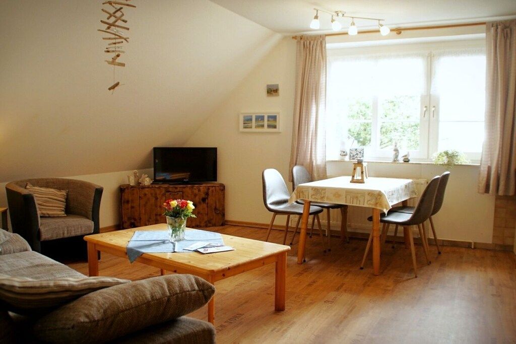 A cozy living room with a sofa, a coffee table, a TV, and a dining area with chairs and a table.