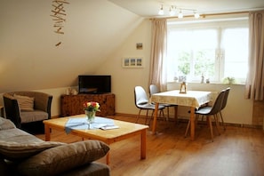 Una sala de estar acogedora con un sofá, una mesa de centro, un televisor y un comedor con sillas y una mesa.