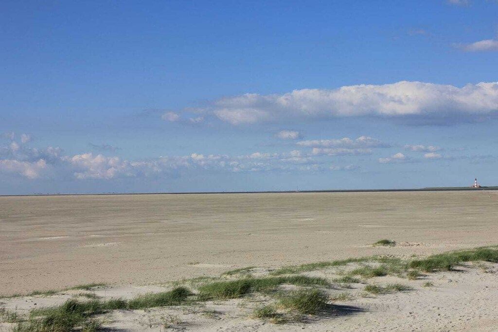A flat, expansive landscape with a distant lighthouse.