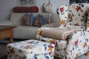 Ein Wohnzimmer mit einer Couch, einem Blumenstuhl und passendem Hocker.