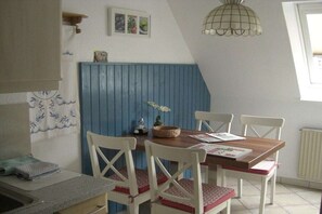 Een eetruimte met een houten tafel, witte stoelen en een blauwe accentmuur.