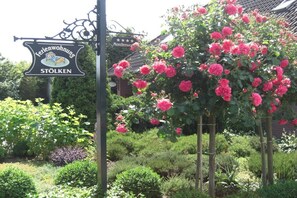 Ein Garten mit einem Schild für 'Stolken' und einem traditionellen Gebäude im Hintergrund.