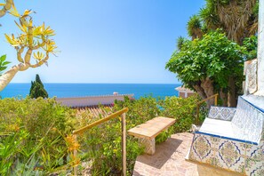A coastal terrace with a view of the sea, a wooden bench, and a tiled wall. - Holiday Home in Nerja With Sea Views (Nerja)