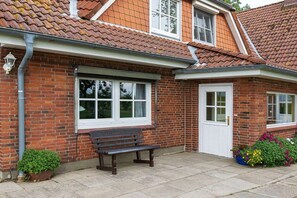 A brick house with a tiled roof, a white door, and a bench outside. - Holiday apartment Hell (Wesselburener Deichhausen)