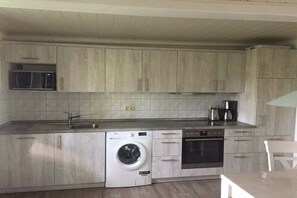 A compact kitchen with a built-in washing machine, a microwave, and a coffee maker. - Holiday apartment Hell (Wesselburener Deichhausen)