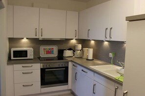 A kitchen with white cabinets, a microwave, a toaster, and a coffee maker. - Holiday apartment with 2 bedrooms (Fehmarn)