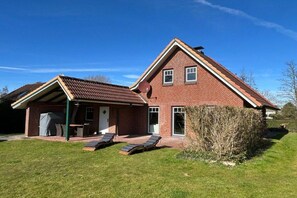 A two-story brick house with a covered patio and a lawn. - Holiday home with 3 bedrooms (Schönberger Strand)
