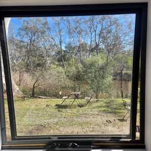 Blick aus dem Fenster auf eine natürliche Landschaft mit Bäumen und einer Wiese.